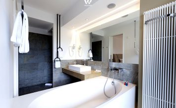 Die weiße Badewanne ergänzt sich ideal mit der dunklen Wandgestaltung